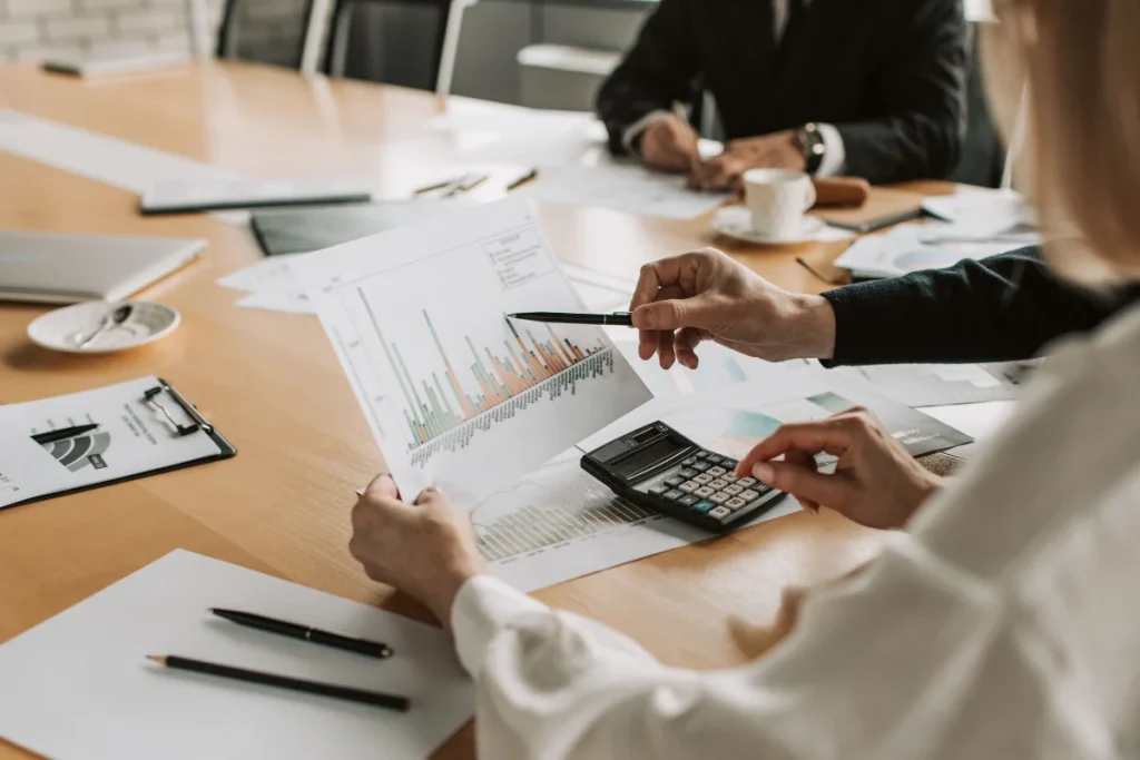 Close-up of business people at a meeting table, analyzing bar charts.