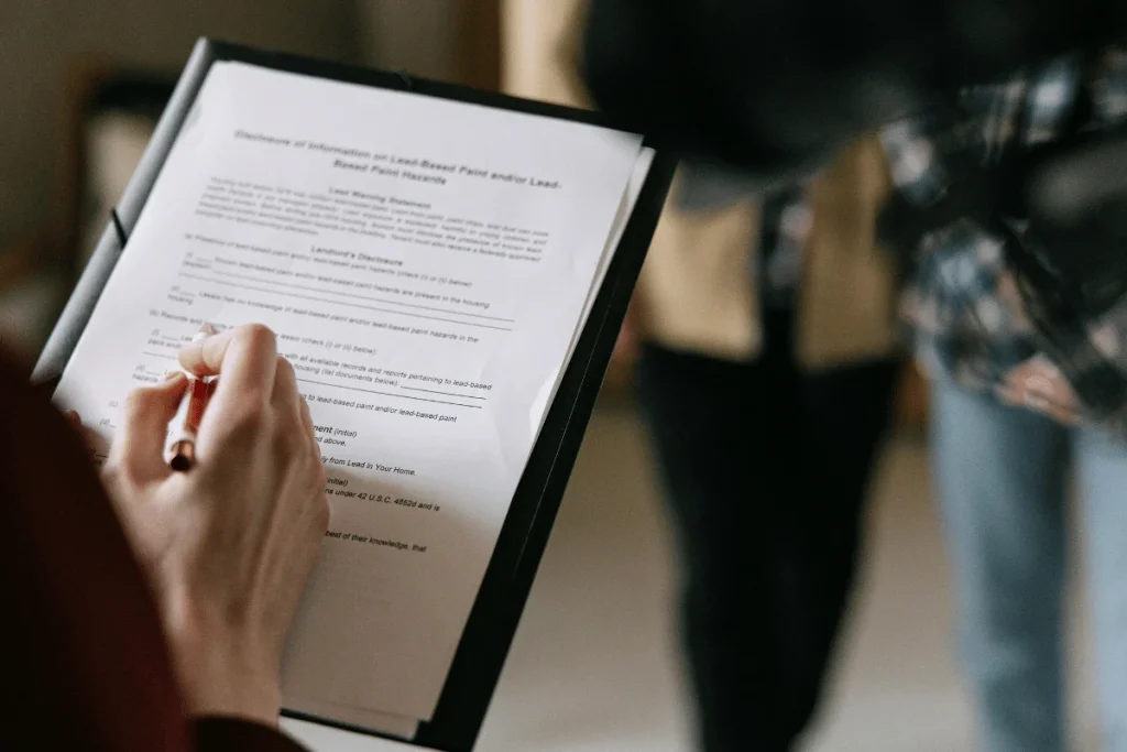 Person holding a clipboard while reviewing and filling out a document.