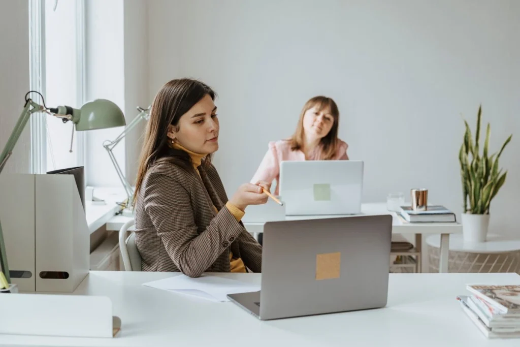 Two people working at laptops in a bright office.
