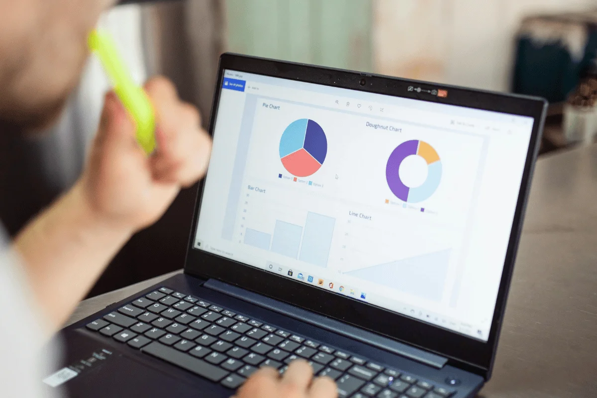 A person analyzes various colorful charts displayed on a laptop screen, focusing on data visualization and analysis.