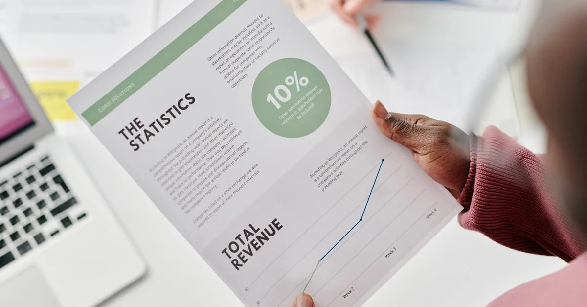Person holding analytics report with 10% growth metric and statistics data on workspace.