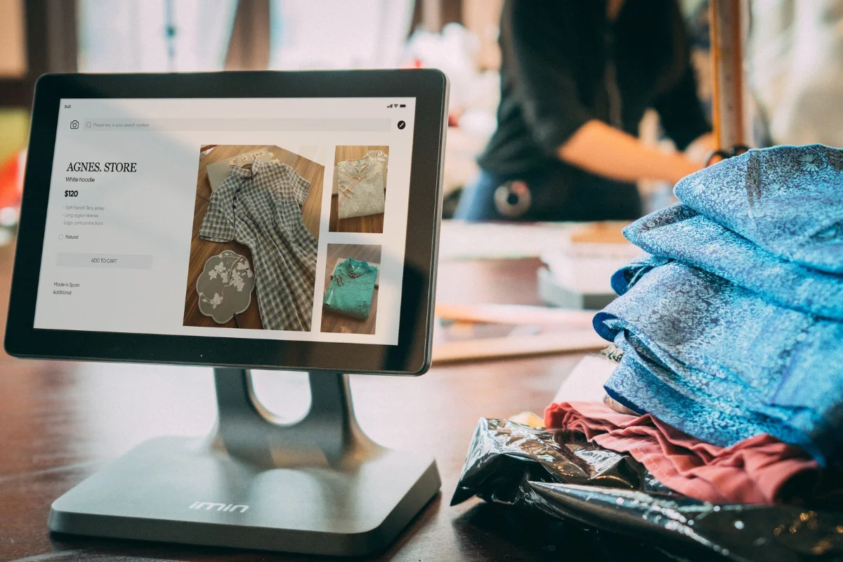 Tablet on a stand displays an online shop page from "Agnes Store" featuring floral dresses.