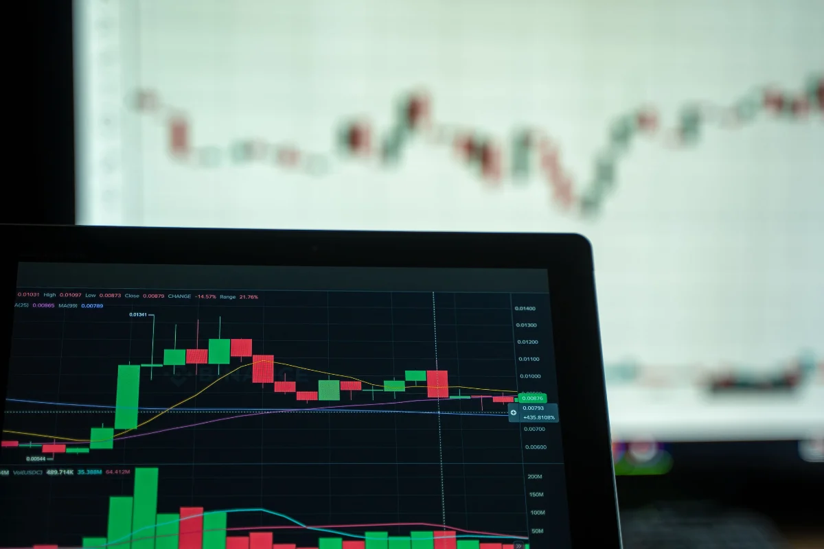 A close-up of a computer screen displaying colorful candlestick charts representing stock market trends, with a blurred chart in the background.