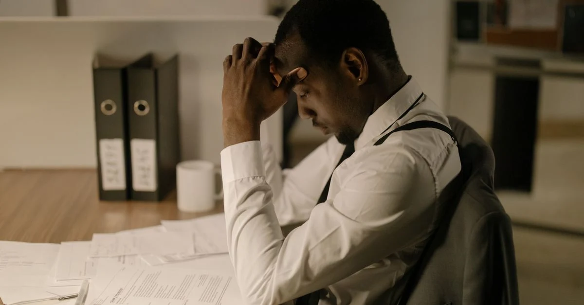Stressed businessman at desk with documents representing ecommerce cash flow challenges and financial difficulties.