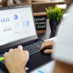 Person reviewing ecommerce financial model dashboard with charts and analytics on laptop screen in office.
