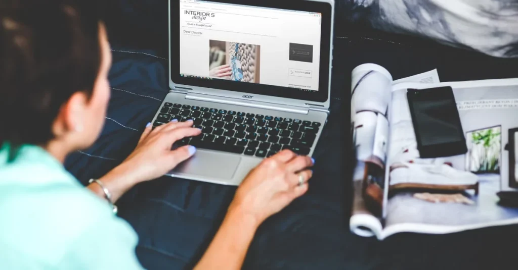 Person reviewing ecommerce marketing analytics dashboard on laptop with design materials and portfolio nearby.