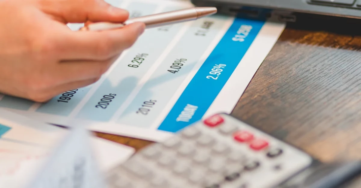Person pointing at ecommerce marketing budget breakdown chart with calculator and laptop on desk.
