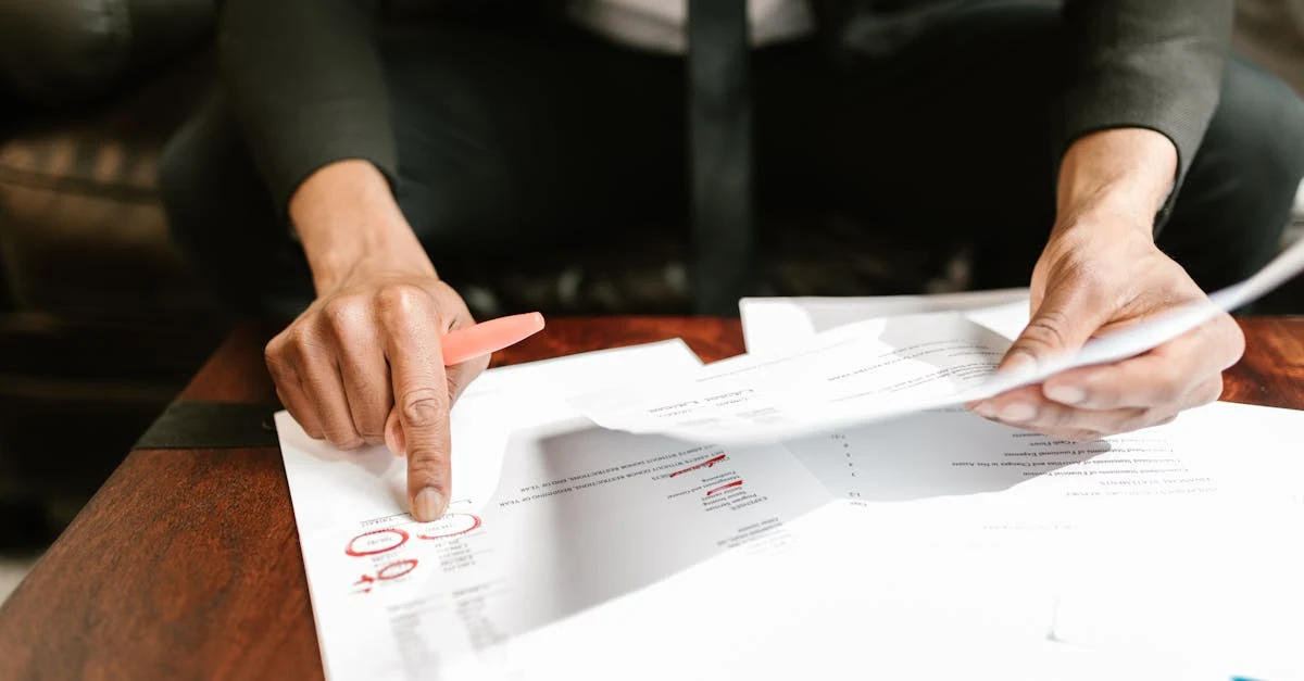 Business professional analyzing ecommerce financial model documents with red markups on wooden desk.